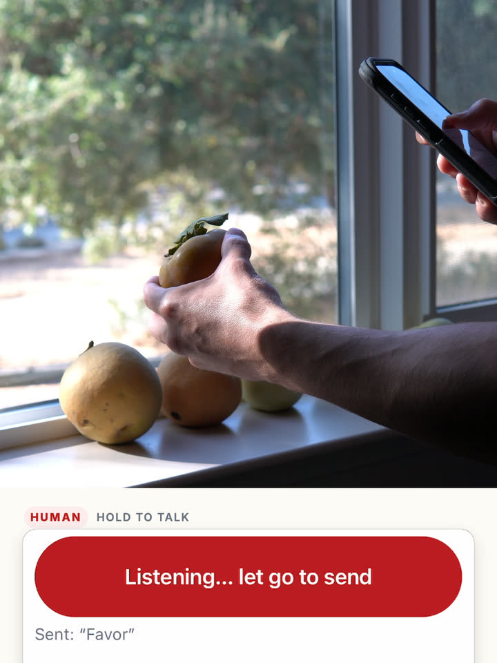 The worker holding the persimmon while pressing Hold to talk; the screen shows the previous attempt was heard as “Favor”.